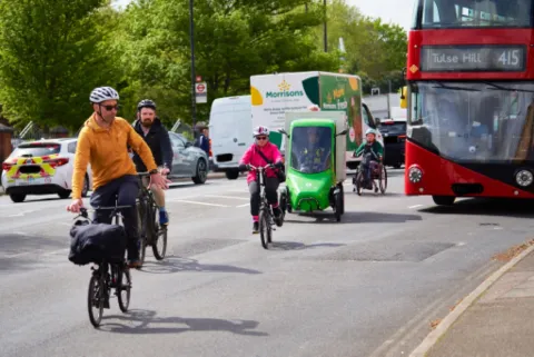 A group of cyclists sharing a road with a van and a bus