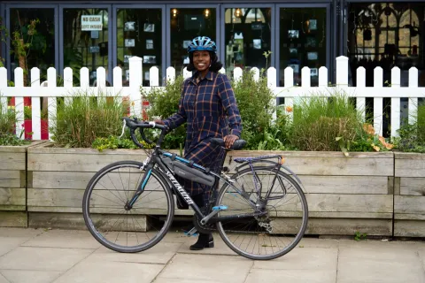 A cyclist in a checked shirt standing beside a bike
