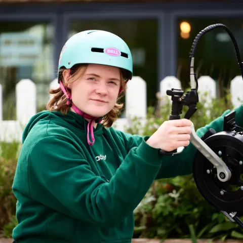A young cyclist in a helmet getting their bike ready to ride.